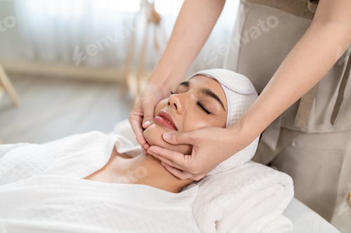 Preview: Beautiful woman getting head and facial massage treatment at beauty spa.