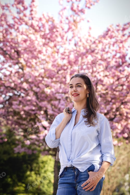 Preview: Beautiful smiling woman on the background of lilac pink cherry blossoms