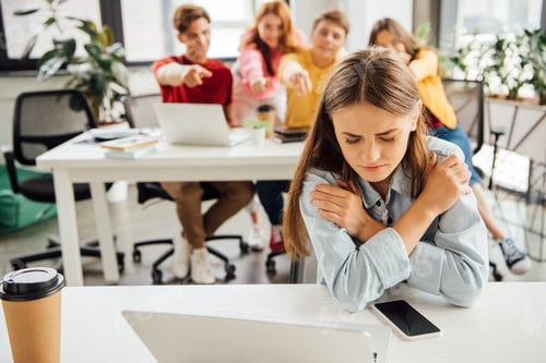 Preview: schoolchildren laughing while bullying sad girl on foreground
