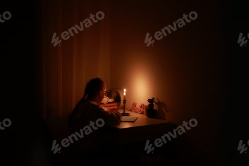 Preview: Schoolgirl uses candlelight to writes and reads in darkness without electric lights at home. Teen