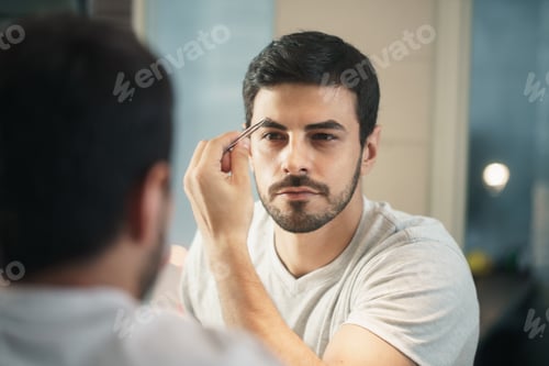 Preview: Latino Man Trimming Eyebrow For Body Care In Bathroom