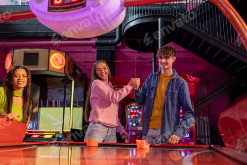 Preview: Friends Celebrating After Air Hockey Game at Arcade