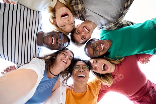 Preview: Selfie from below large diverse group friends posing hugging in circle looking excited at camera.