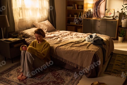 Preview: Young Woman Sitting on Floor Reflecting in Cozy Bedroom Interior