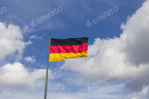 Preview: Pole with a waving German flag on the blue cloudy sky background