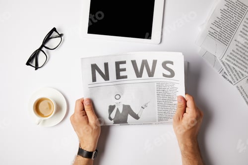 Preview: cropped view of businessman reading newspaper at white table with digital tablet, coffee and