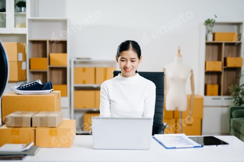Preview: Young business owner woman prepare parcel box and standing check online orders for deliver