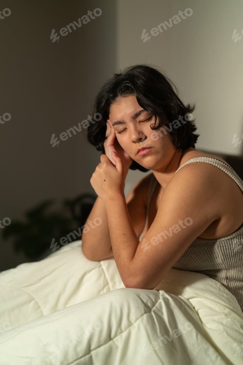 Preview: Young woman suffering from insomnia and headache in bed at night