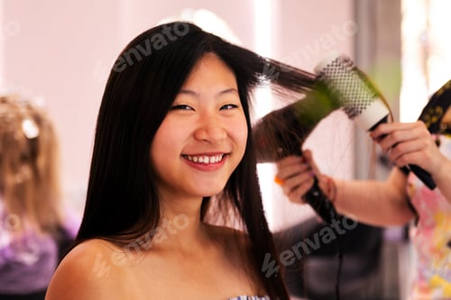 Preview: stylist combing woman's hair with brush and dryer