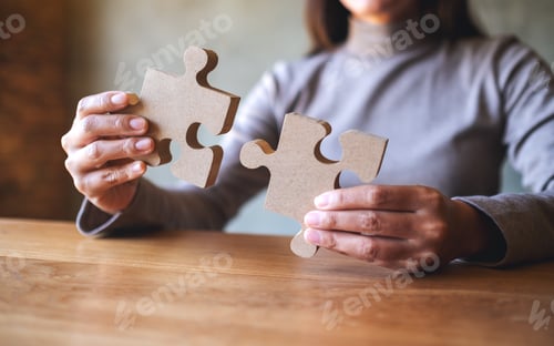 Preview: Closeup image of a woman holding and putting a piece of wooden jigsaw puzzle together