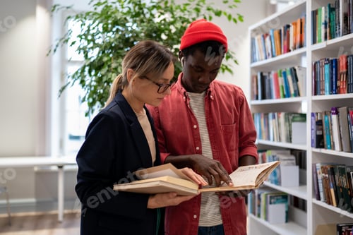 Preview: Multiethnic students friends girl and guy standing reading book studying near bookshelves in library