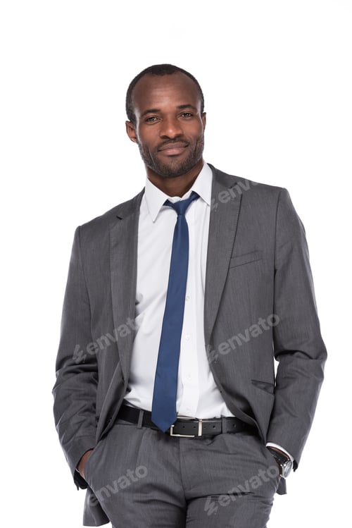 Preview: smiling african american businessman in suit with hands in pockets isolated on white