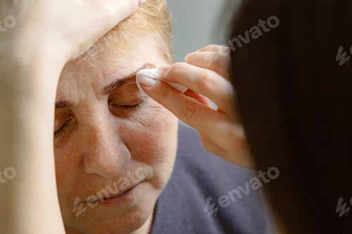 Preview: A cosmetologist paints the eyebrows of an elderly woman.