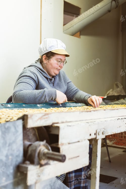 Preview: Woman selecting beans in front of a conveyor belt