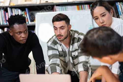 Preview: Young diverse creative designer team watching project on laptop