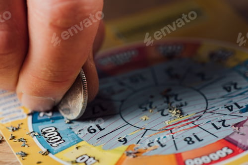 Preview: cropped view of gambler scratching lottery ticket with silver coin