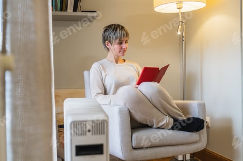 Preview: Woman relaxing at home reading digital tablet in armchair