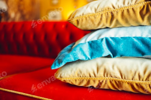 Preview: Orange, blue and beige pillows on a red comfortable sofa