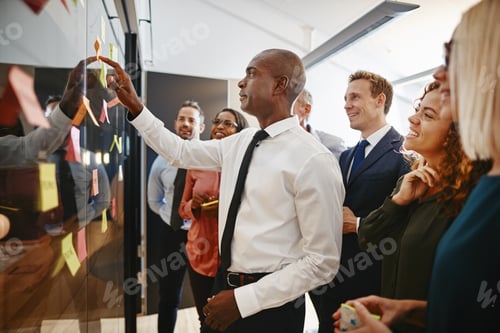 Preview: Young African businessman and his team brainstorming with sticky notes