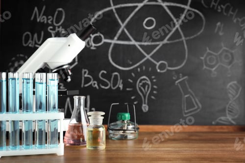 Preview: Laboratory glassware and microscope on table near chalkboard. Chemistry concept