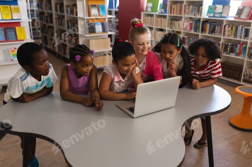 Preview: Side view of schoolkids studying together on laptop at table in school library