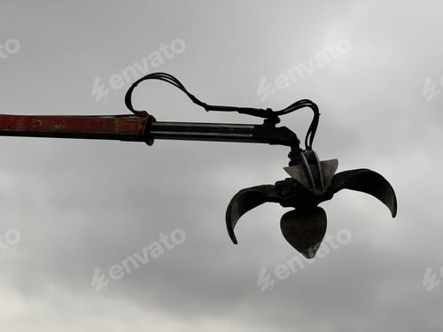 Preview: Metallic hydraulic claw crane against the cloudy rainy sky