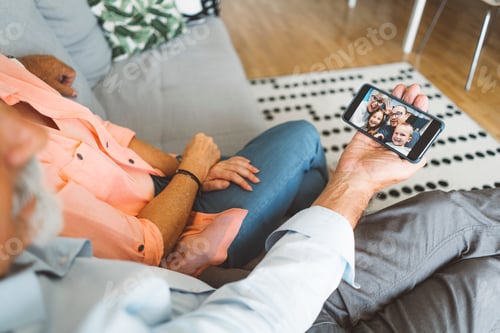 Preview: Senior couple resting on the couch while talking to family over video chat on the phone
