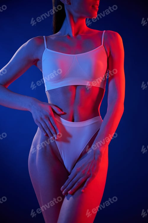 Preview: Blue and red colors. Young woman in underwear is in the studio with neon lights
