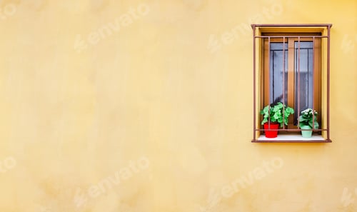 Preview: Vertical image of the facade of a rural house with a barred window and flowerpots