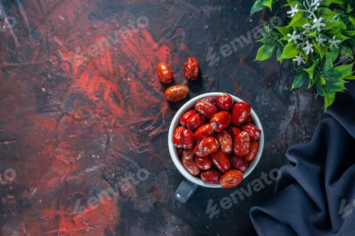 Preview: Above view of fresh raw silverberry fruits inside and outside of a gray cup and flower pot dark
