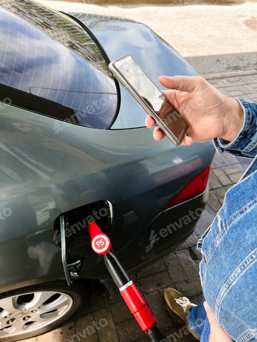 Preview: Man making contactless payment using smartphone for refueling car at gas station.