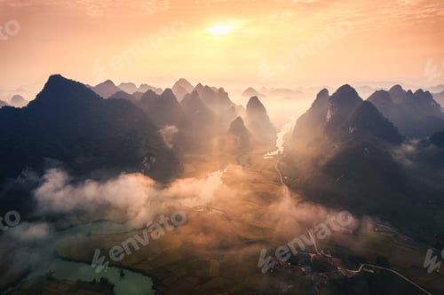 Preview: Sunrise over mountain range with foggy on rural village and river flows through in Phong Nam Valley