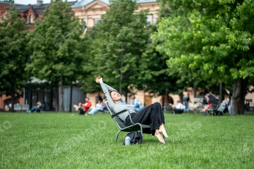 Preview: Laid-back lazy and drowsy woman stretching and napping in park lounger during hot summer day