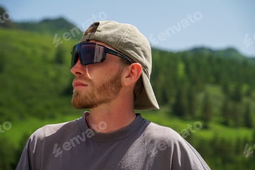 Preview: A portrait of a guy wearing glasses against a backdrop of mountains, in profile with a beard