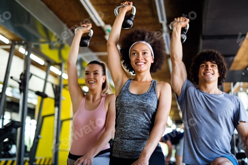 Preview: Group of fit people working out in a gym. Multiracial friends exercising together in fitness club.