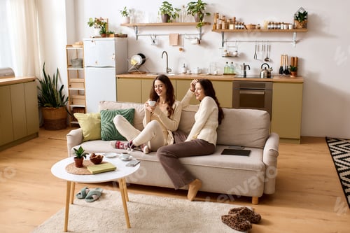 Preview: Twin sisters enjoying a cozy moment together in their stylish home living room bliss