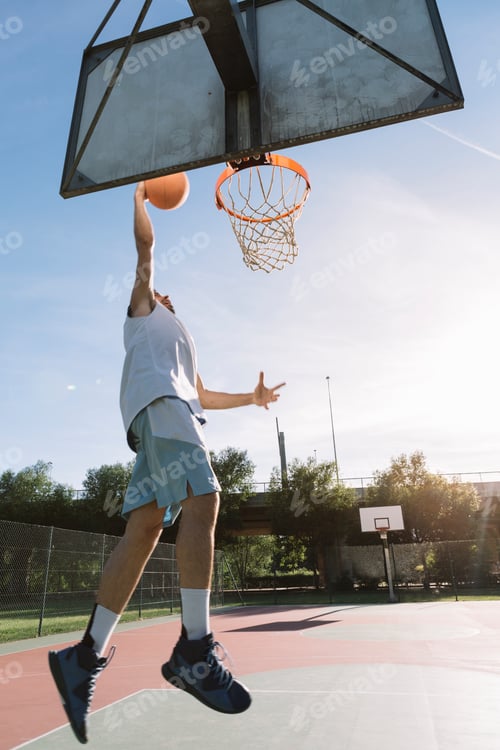 Preview: Athletic Man Slam Dunks Basketball at Outdoor Court