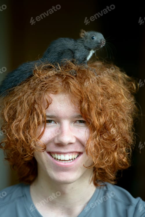 Preview: Portrait of happy redheaded teenage boy with squirrel on his head