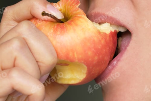 Preview: Person taking a bite of a red apple, capturing the freshness and appeal of healthy snacks. Concept