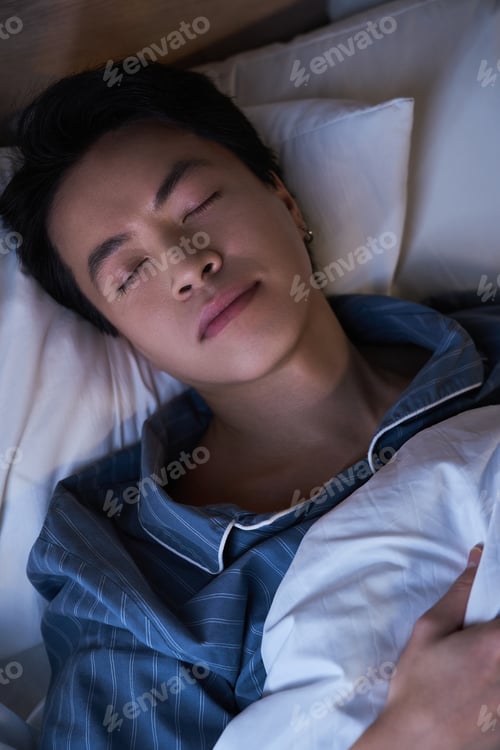 Preview: Relaxed Asian man peacefully resting in a modern apartment in the evening hours