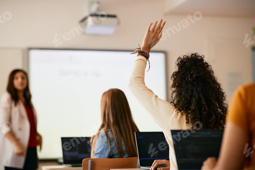 Preview: Back view of student raising her hand to ask a question during class in high school.