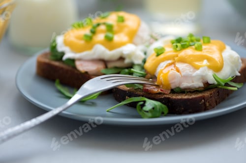 Preview: Close up eggs Benedict with arugula, bacon and hollandaise sauce on gray wooden background