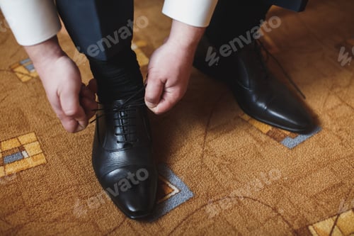Preview: Man's hands tying shoelace of his new shoes.