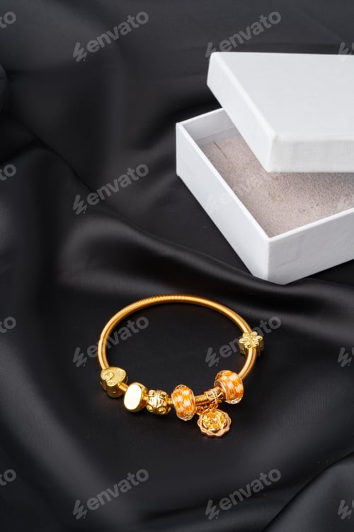 Preview: Golden bracelet with jewelry box on black silk background