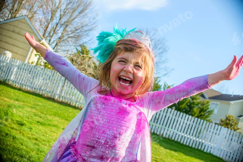 Preview: Girl in gown with feather fascinator playing outdoors