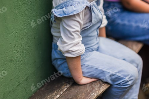 Preview: Young shy girl sitting on wooden bench, during environmental education at animal sanctuary