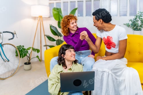 Preview: Transgender person and lesbian couple using laptop together at home