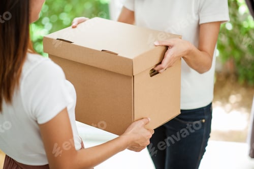 Preview: Close up of two women's hands helping each other moving boxes into their new home.