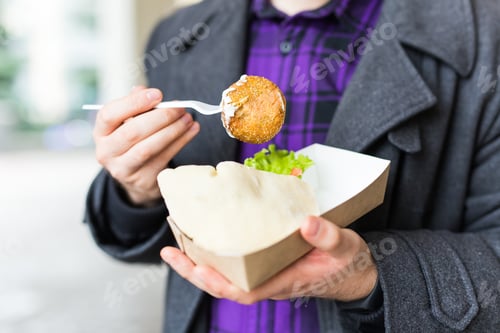 Preview: Close-up of man holding one-off plate with traditional delicious jewish food falafel made of