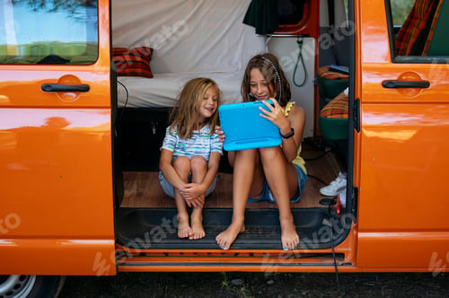 Preview: Two sibling boys using the tablet on a wonderful day camping in a van. Vanlife concept.